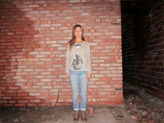 Молодая леди показывает стриптиз на фоне кирпичной стены
